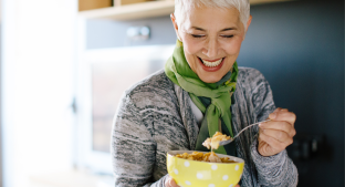 Woman smiling and enjoying a bowl of cereals